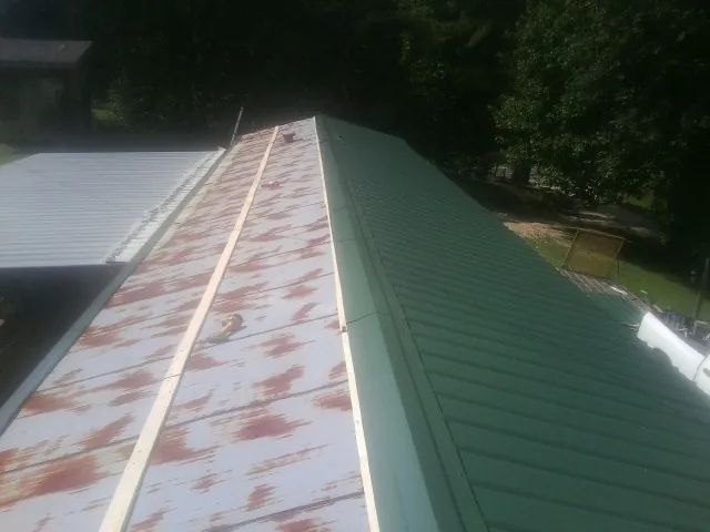 Old rusted panels beside newly installed green metal roofing — Wind Damage Roof Repair by Roofing Brothers in Carmichaels