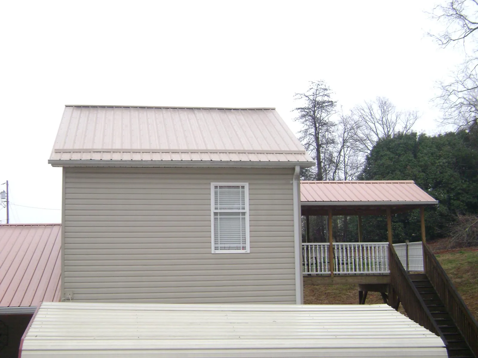 Tan metal roofs on a two story addition and attached porch, from a Roof Replacement job in Carmichaels