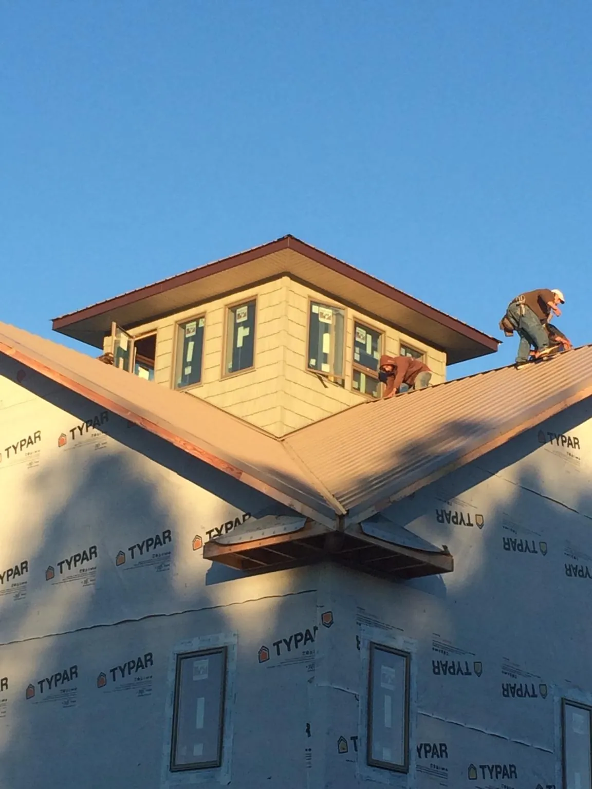 Roofers working around a rooftop cupola on a new metal roof at sunset — Roof Waterproofing in Carmichaels by Roofing Brothers